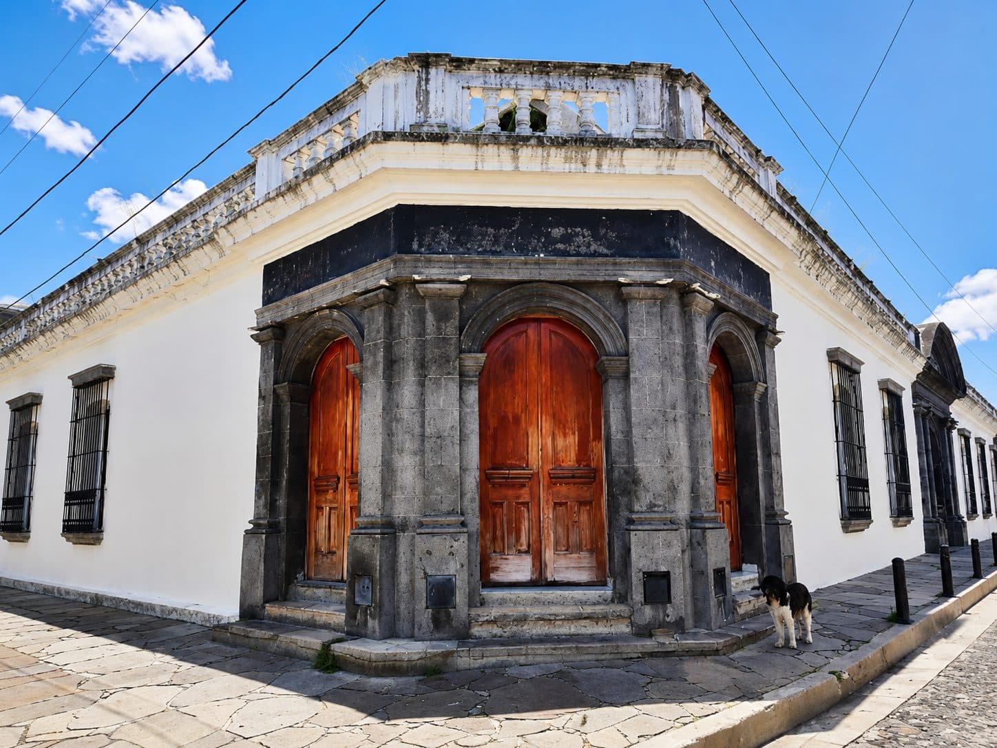 Arched timber double doors on a colonial corner building, off a stone street
